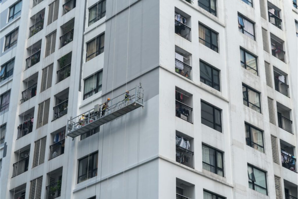 workers painting exterior of high rise- building